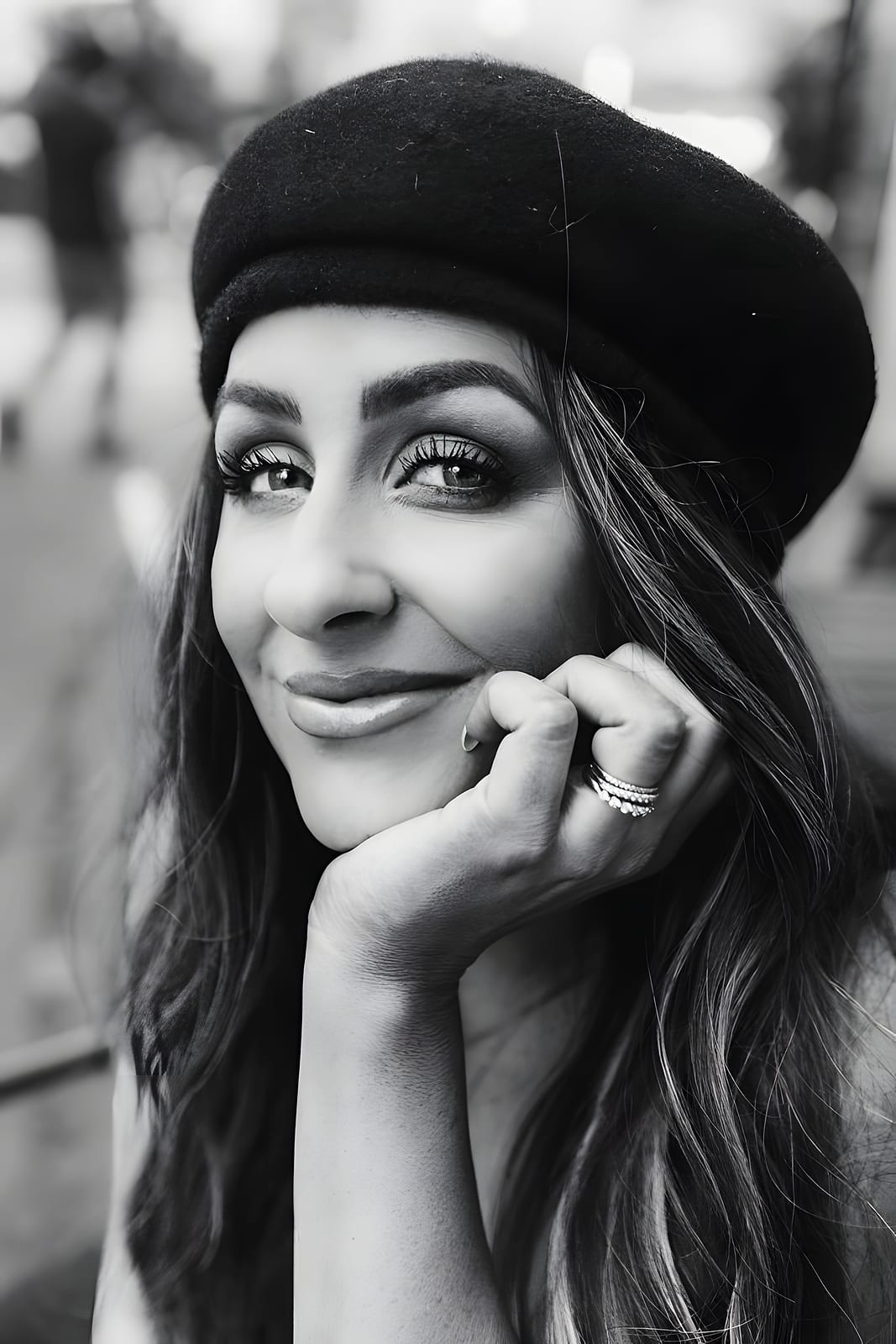 Black and white portrait of Cate smiling in a beret, chin resting on her hand