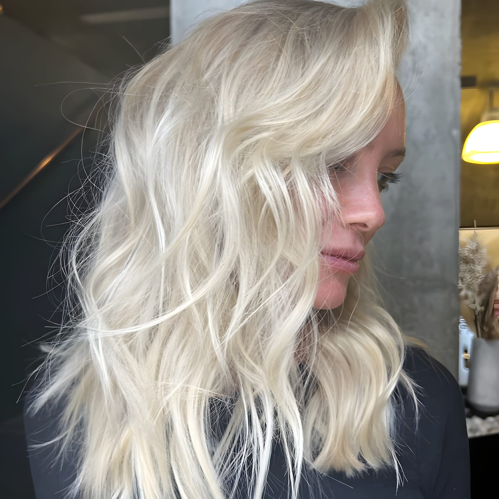 Side profile of a woman with wavy platinum blonde hair in the salon